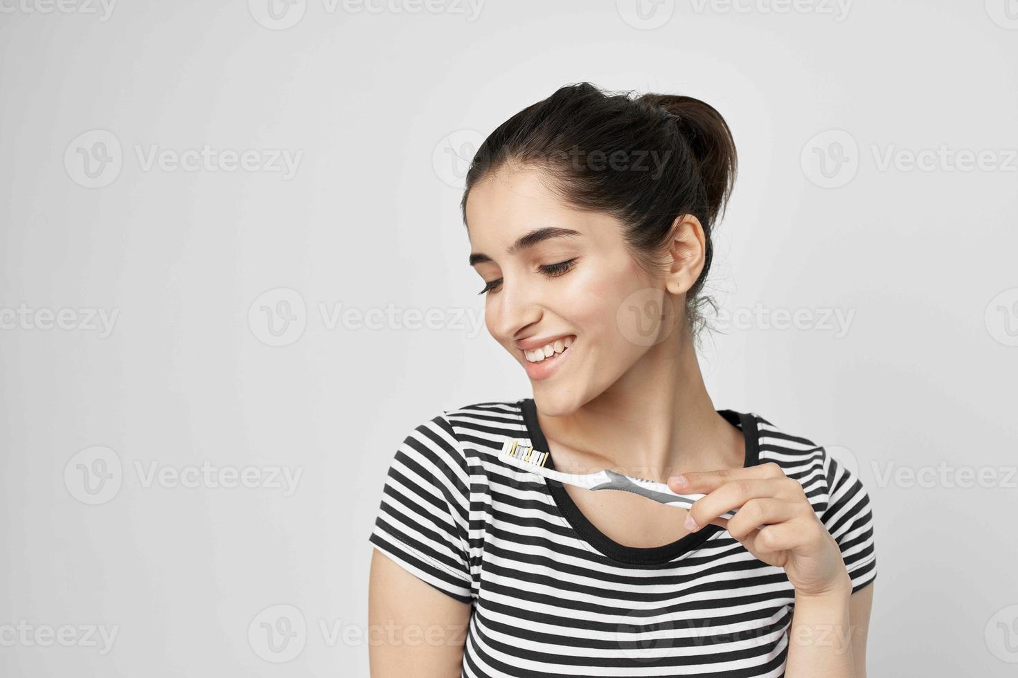 alegre mujer en un a rayas camiseta cepillo de dientes en mano aislado antecedentes foto