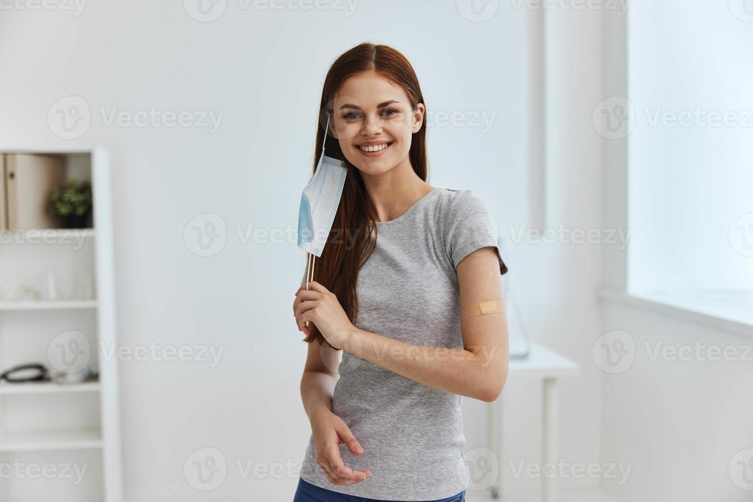 woman in medical mask smiling and adhesive plaster on shoulder covid passport coronavirus model photo