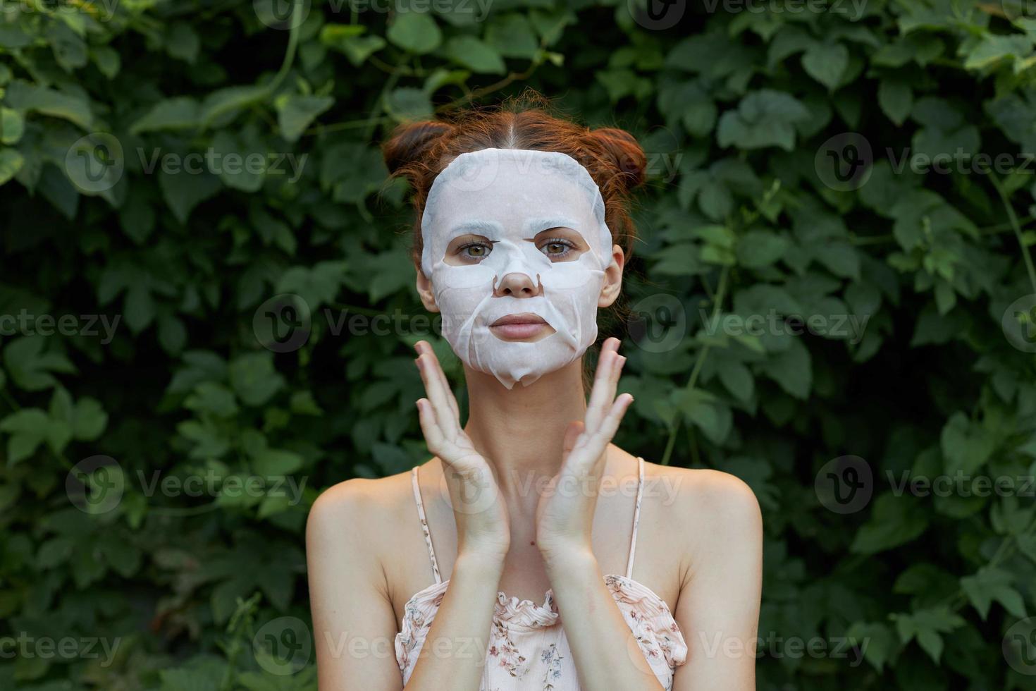 Beautiful woman Anti-wrinkle mask Hands near the face and a light shirt rejuvenation leaves in the background photo