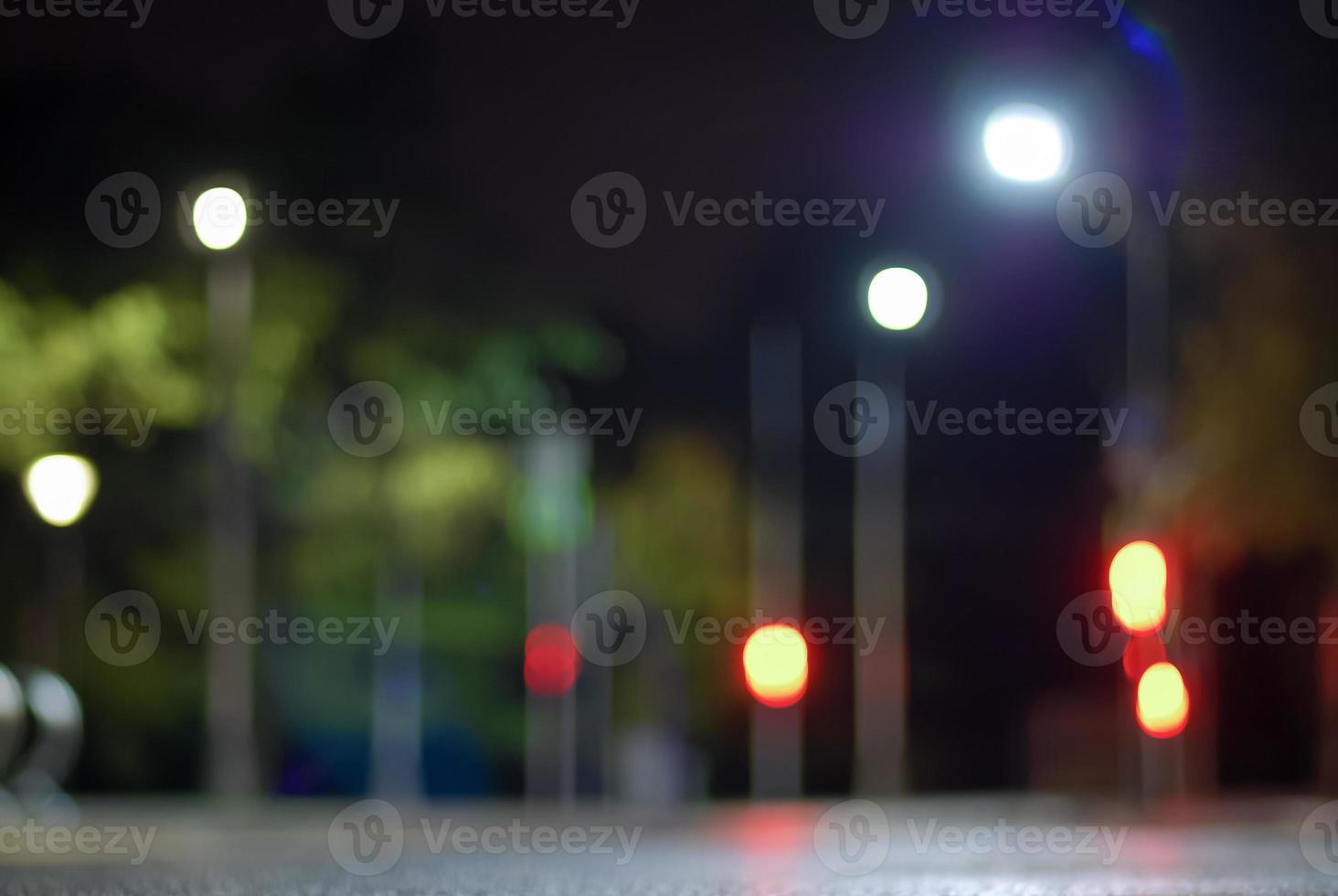 Blurry traffic lights background at night, empty city street defocused view photo