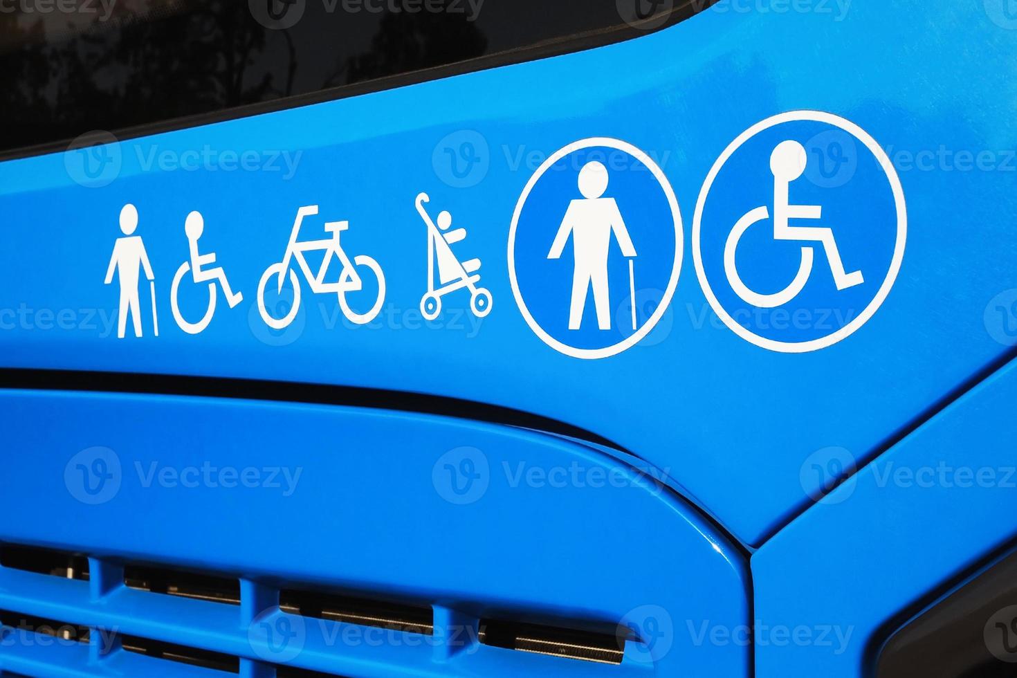 Disabled sign, elderly people, baby carriage and bicycle icons on city bus. Public transportation accessibility concept photo