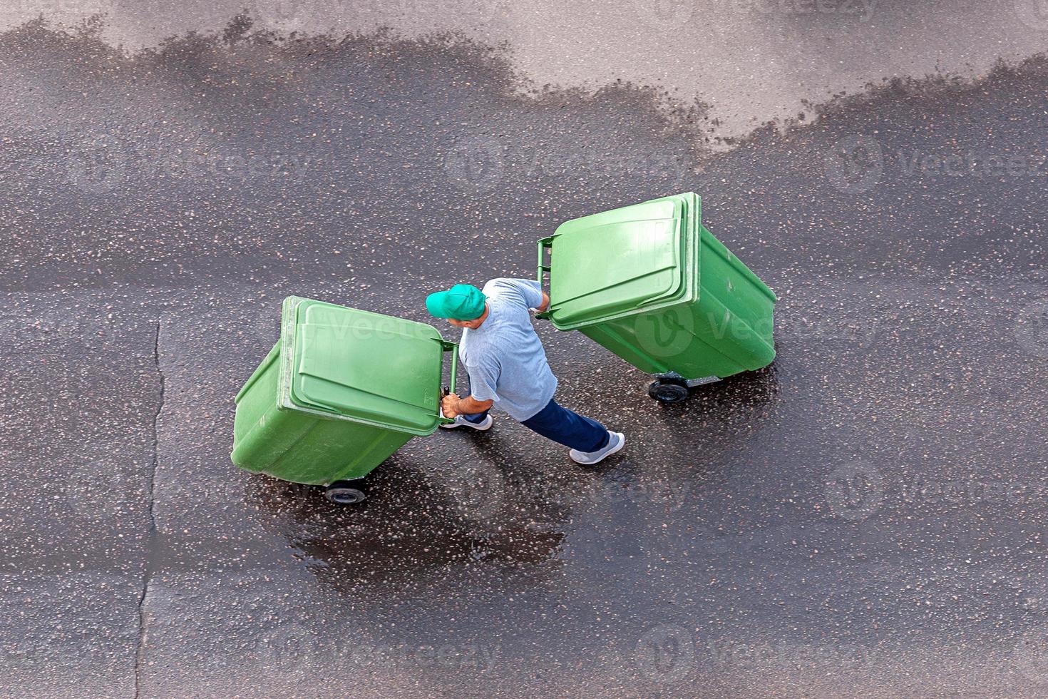 garbage man at work moving trash containers, top view photo