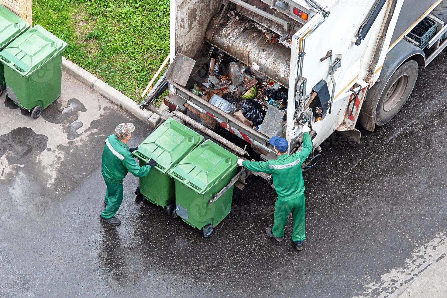 dos trabajadores cargando mezclado Doméstico residuos en residuos colección camión foto