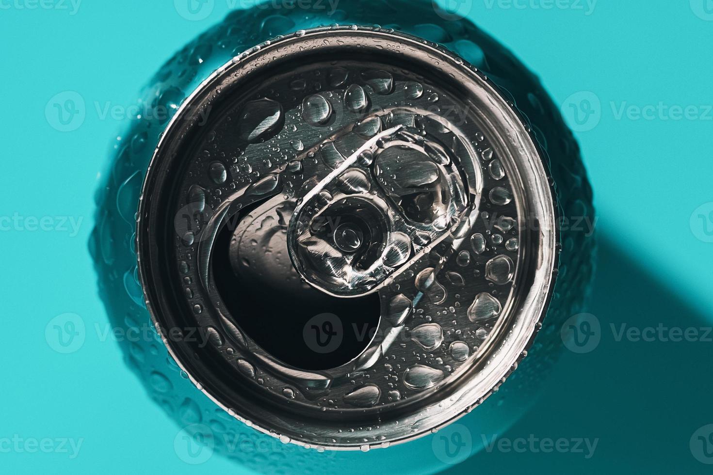 Cyan blue open soda can in shadow and light covered with water drops photo