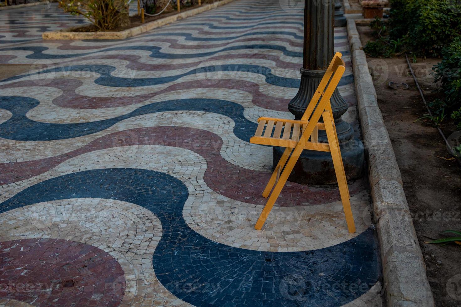 Explanada promenade in Alicante Spain landmark with wooden empty chair on mosaic photo