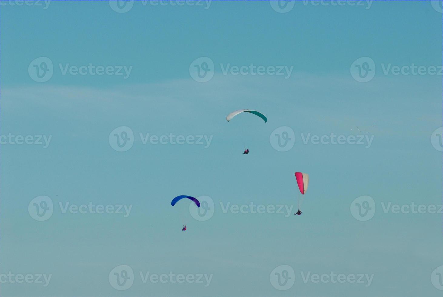 paragliders in the blue cloudless sky photo