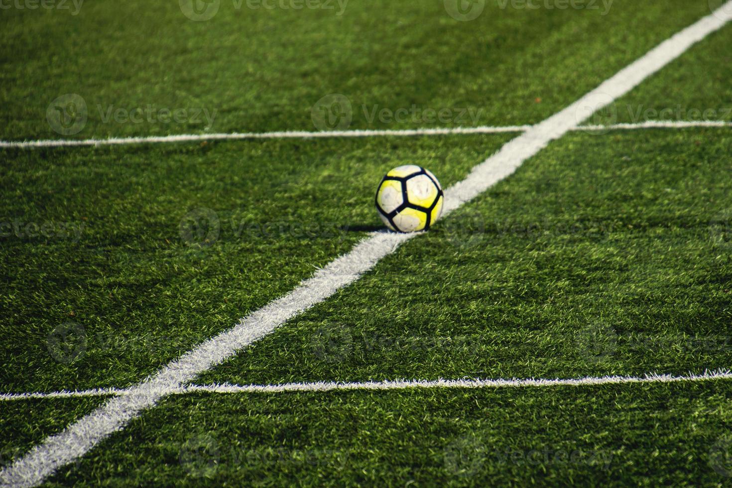 football lying on a green field with artificial turf on a beautiful  day photo