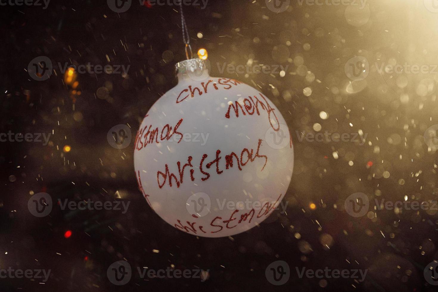 white bauble with red inscription merry christmas on a festive background photo