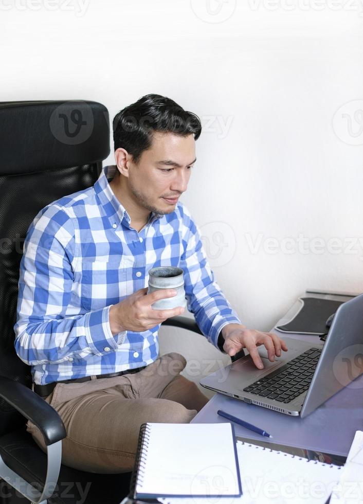 A man in a checked shirt working from home at a desk photo