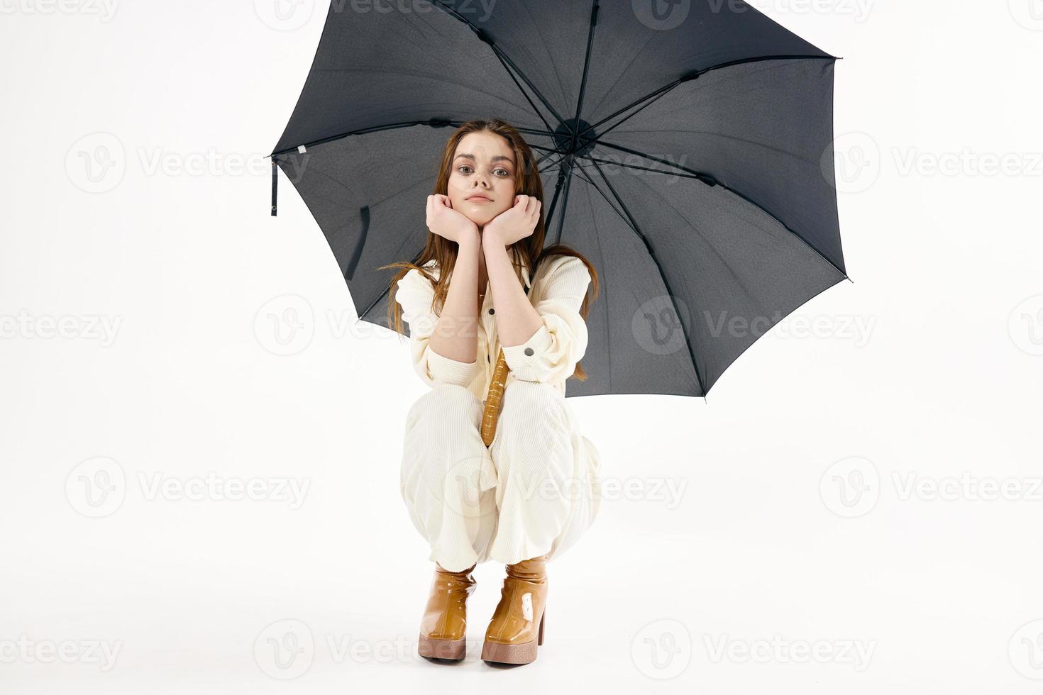 pretty woman with open umbrella squatting fashion studio photo