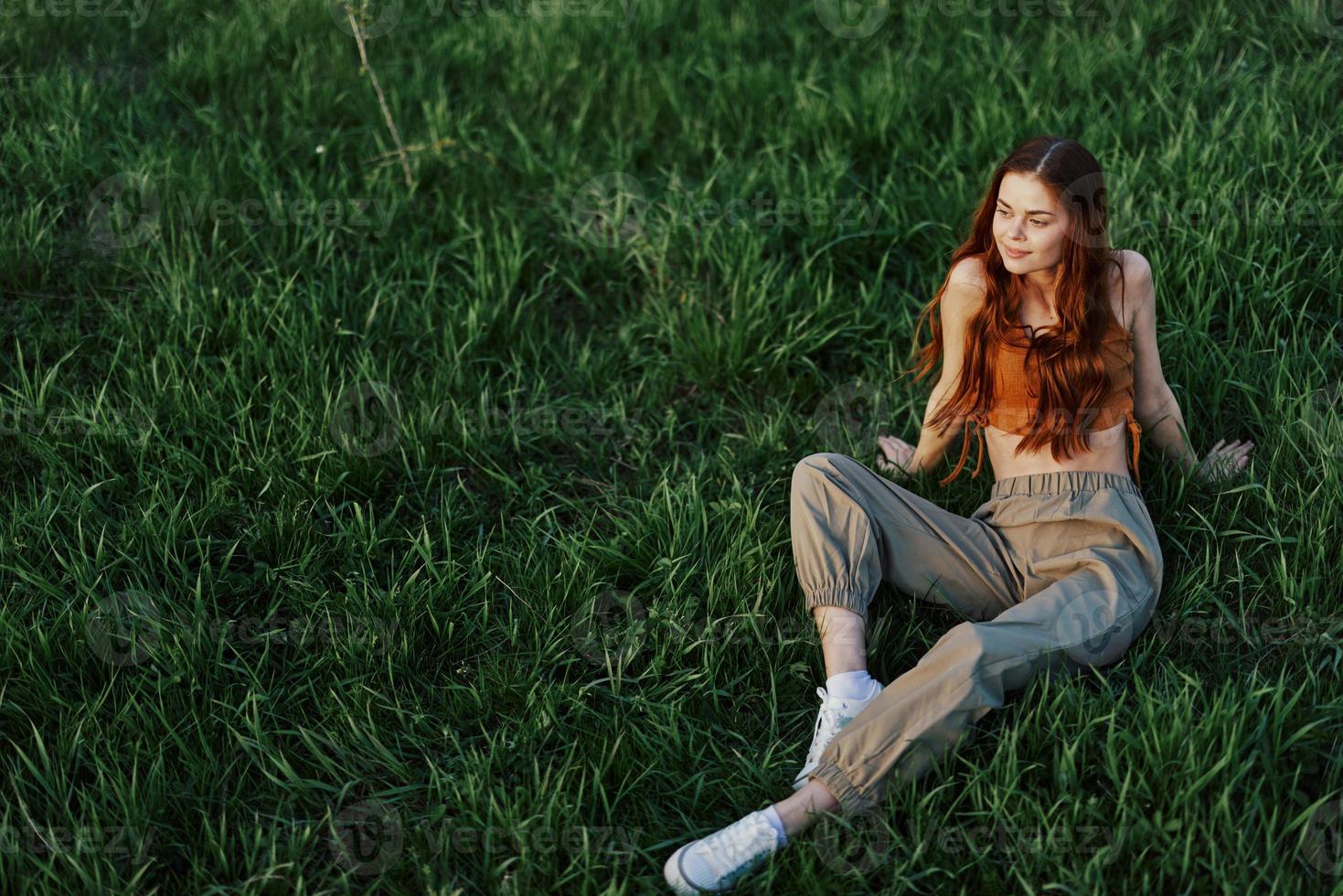 A girl sits on the grass in the park and enjoys the beautiful view of the summer sunset photo