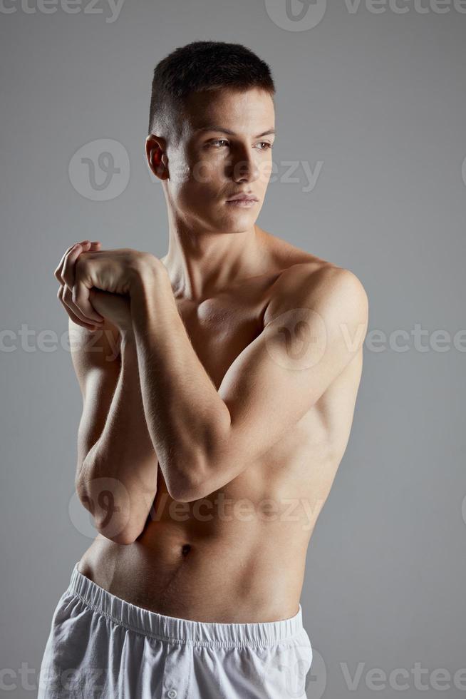 bodybuilder joined hands near chest on gray background photo