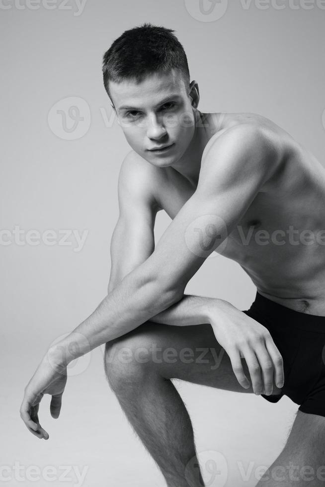 athlete with a pumped-up torso leaning on his knee portrait cropped black and white photography photo
