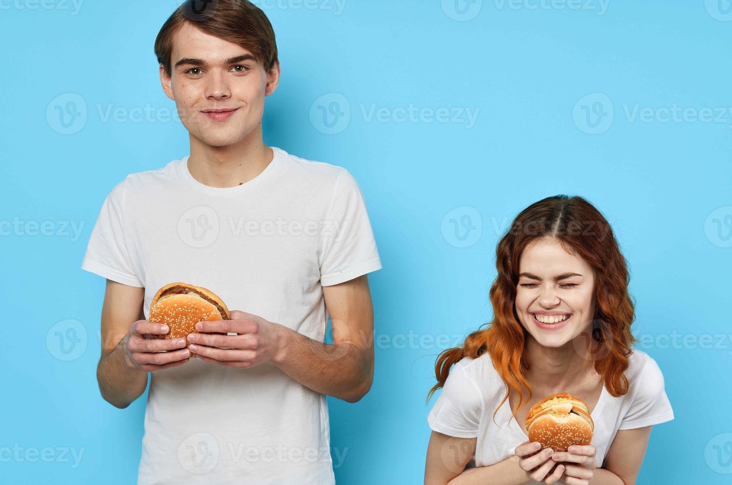 cheerful young couple in white t-shirts having fun fast food hamburgers photo