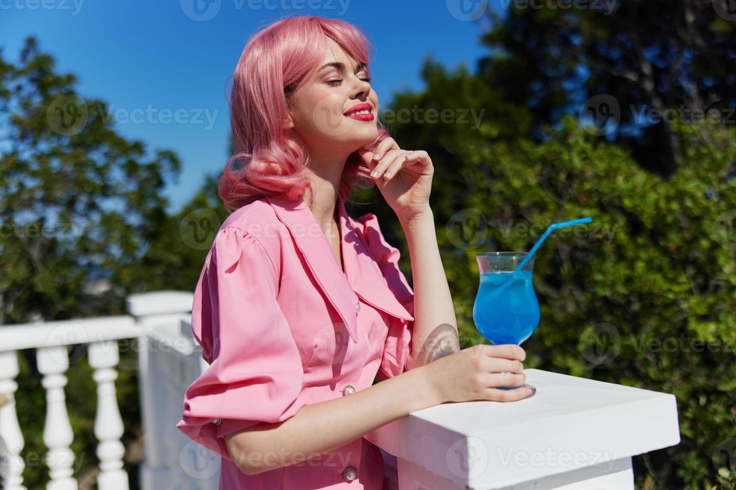 cheerful woman in pink dress outdoors with cocktail Drinking alcohol photo