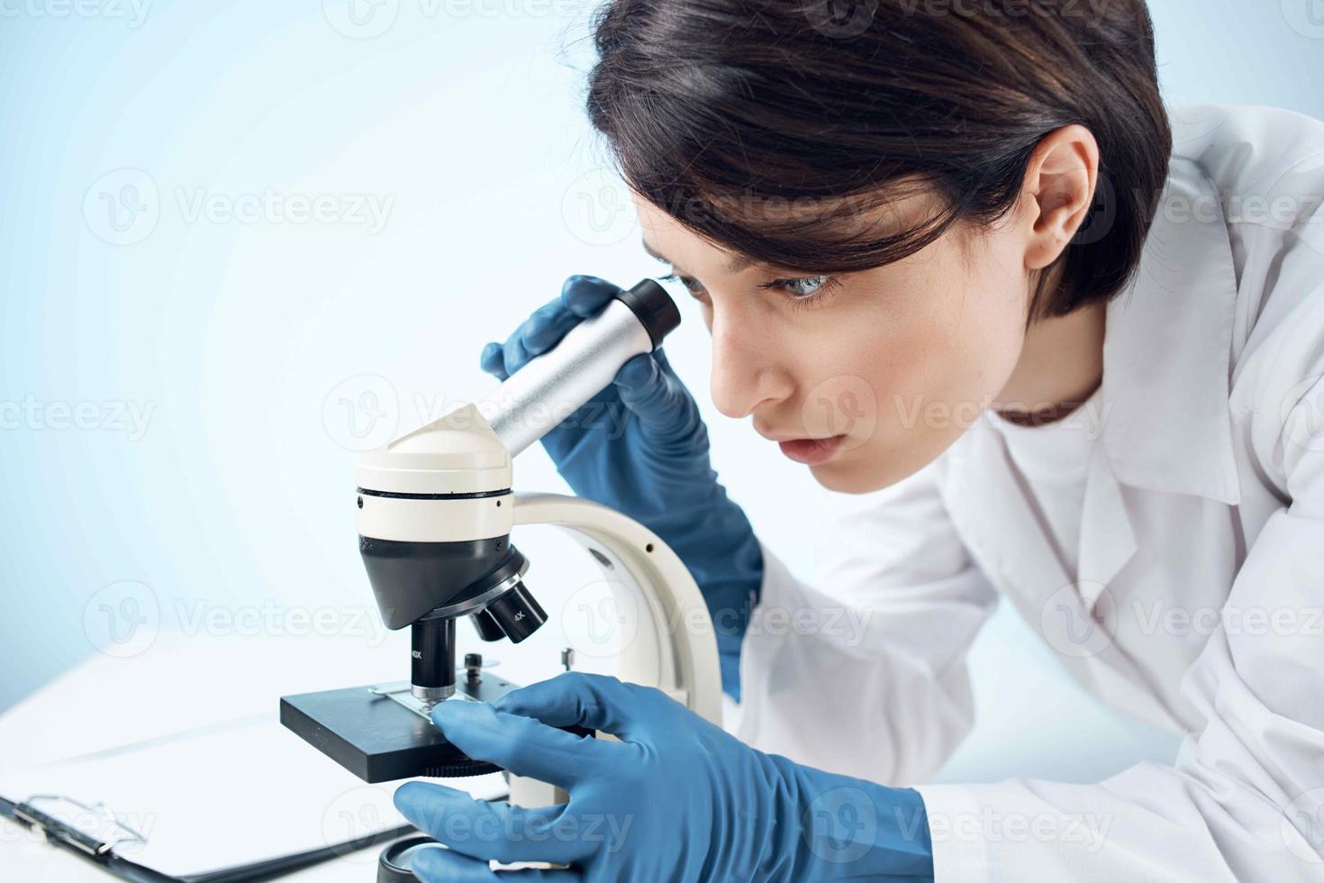 woman looking through a microscope diagnostics science research close-up photo