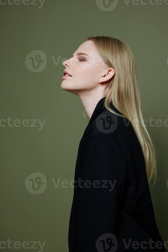 Stylish fashionable charming girl posing in profile looking to the side on a green olive background in the studio. Cool banner for brands photo
