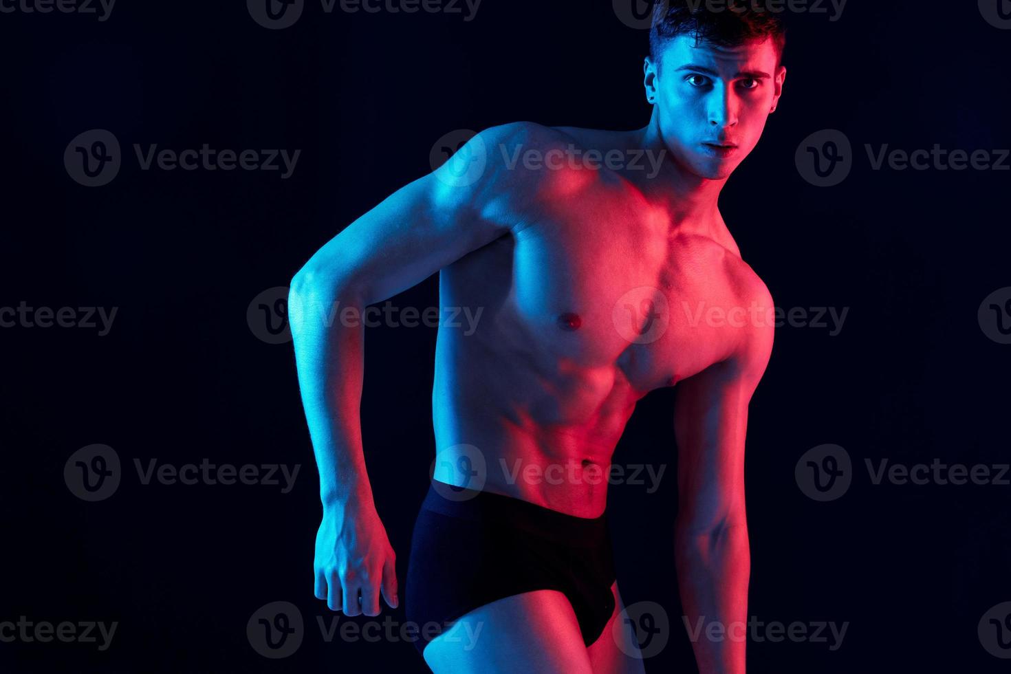 man with pumped-up arm muscles gesturing against a dark background cropped view Copy Space photo