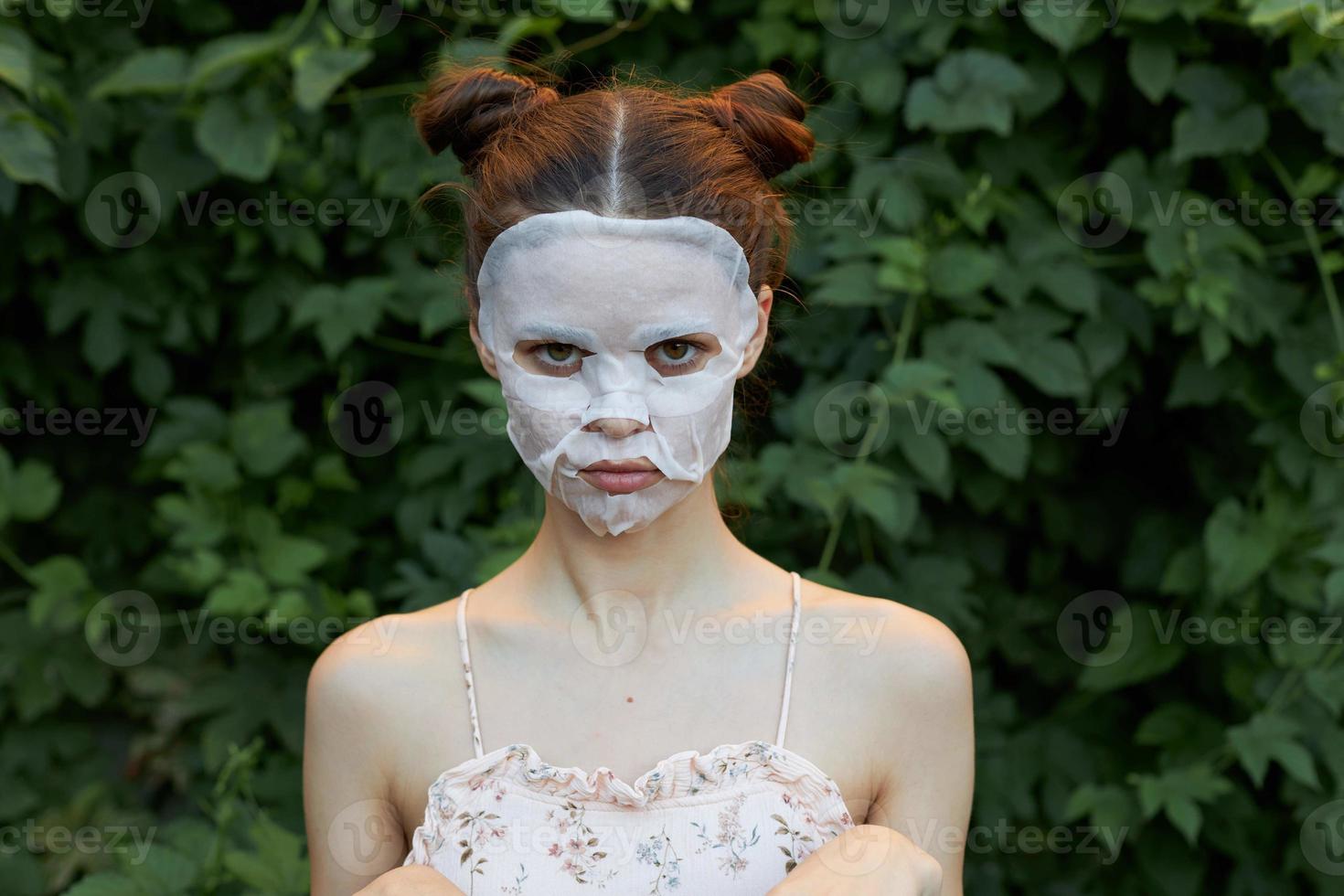 Nice girl cosmetic mask Offended glance green bushes skin care leaves in the background photo