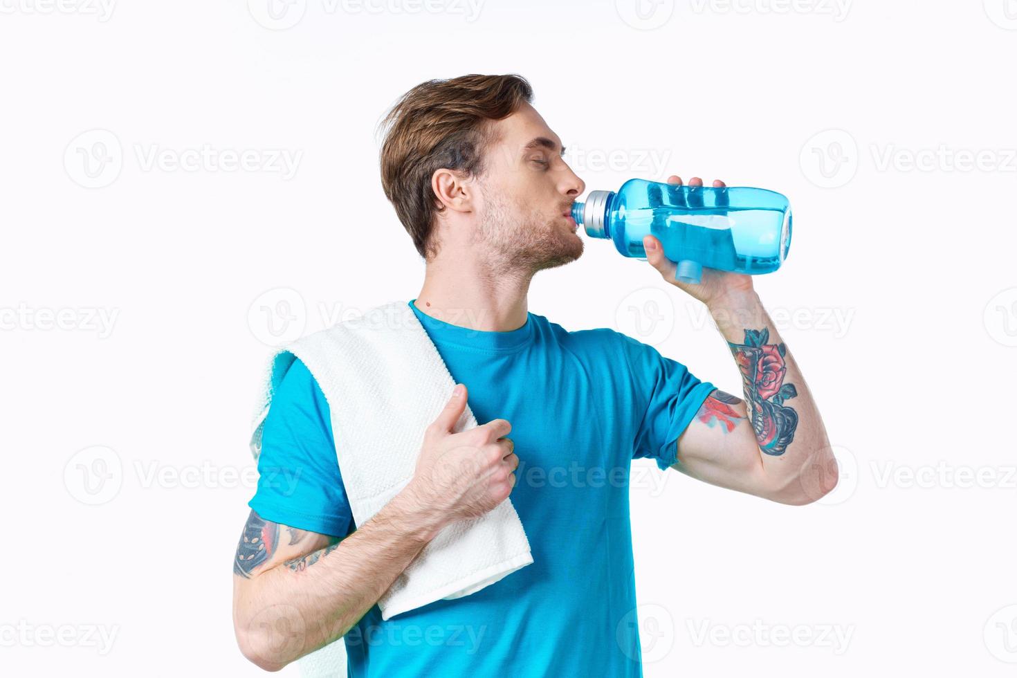 man athlete drinks water from a bottle on a white background and a towel on his shoulder photo