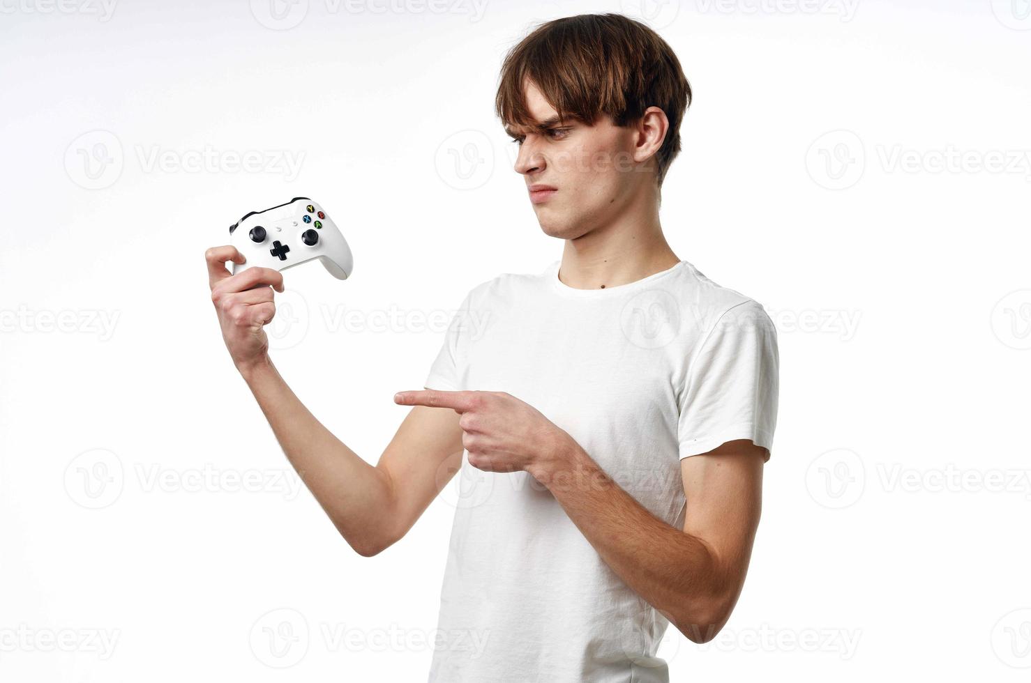 young guy in a white t-shirt Joystick in the hands of the game emotions light background photo