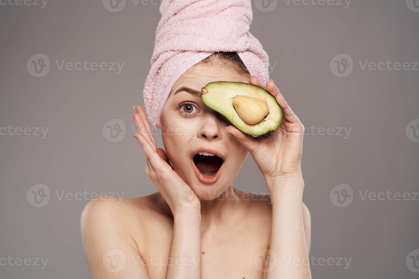 Cheerful woman wearing pink towel on avocado health head photo