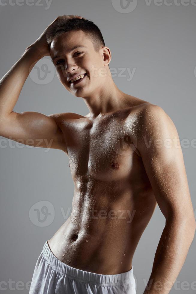 an athlete in white shorts and with a naked torso holds his hand on his head photo