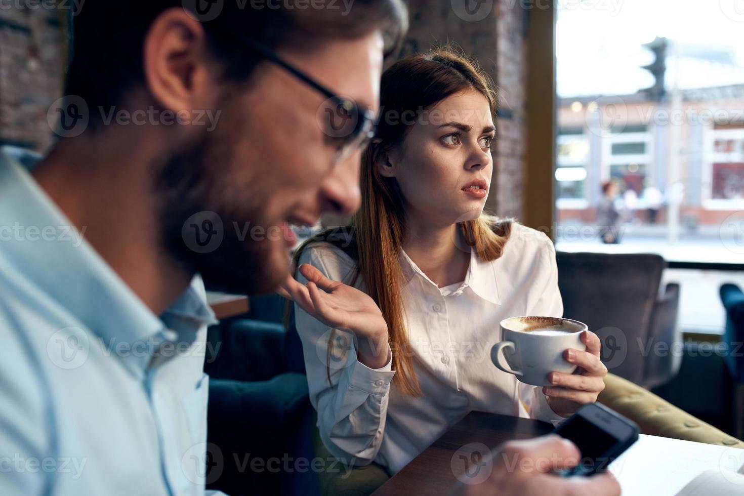 negocio hombres y mujer sentar a el mesa con el teléfono chateando desayuno foto