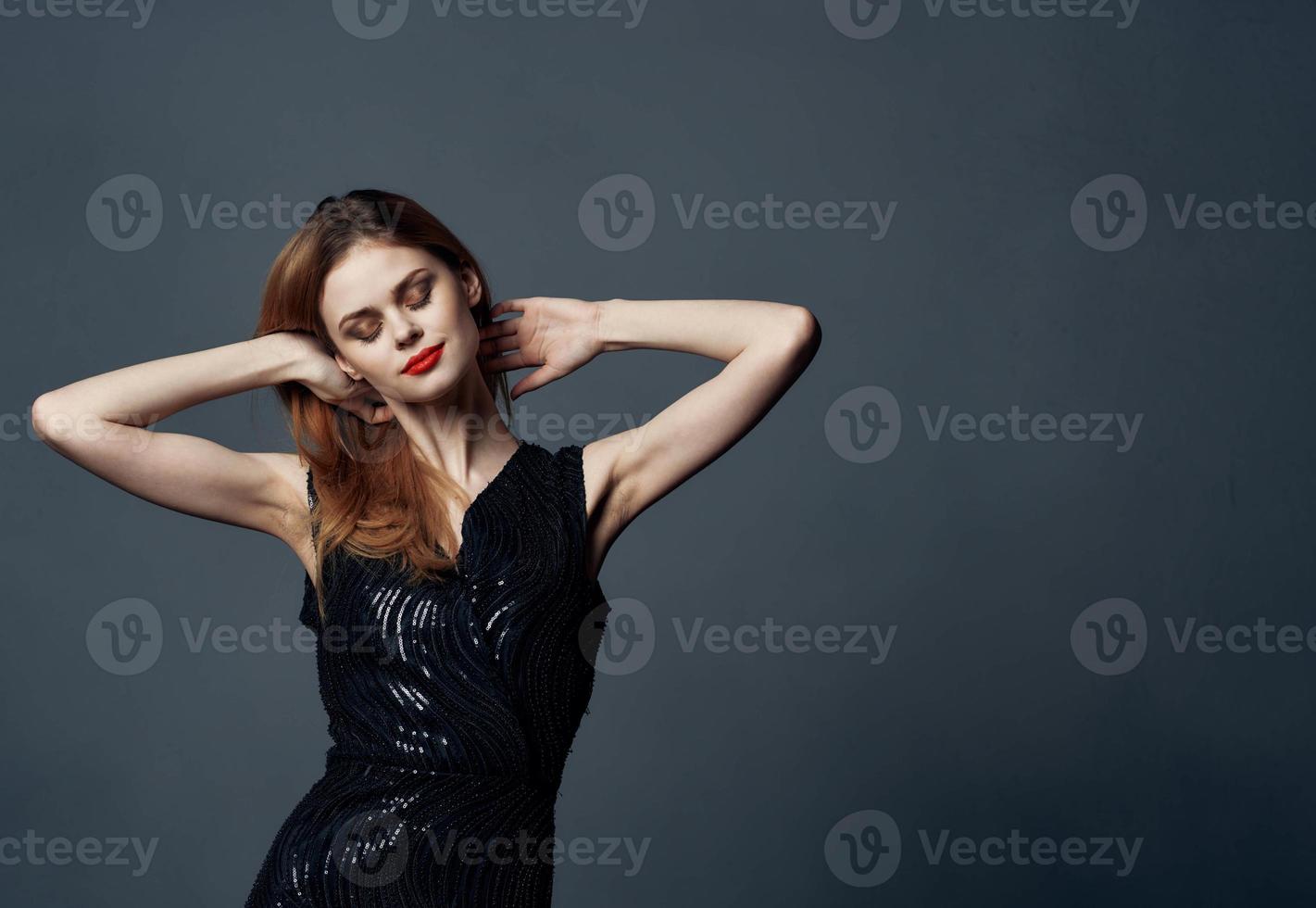 A beautiful lady in an evening dress on a gray background gestures with her hands Copy Space Model photo