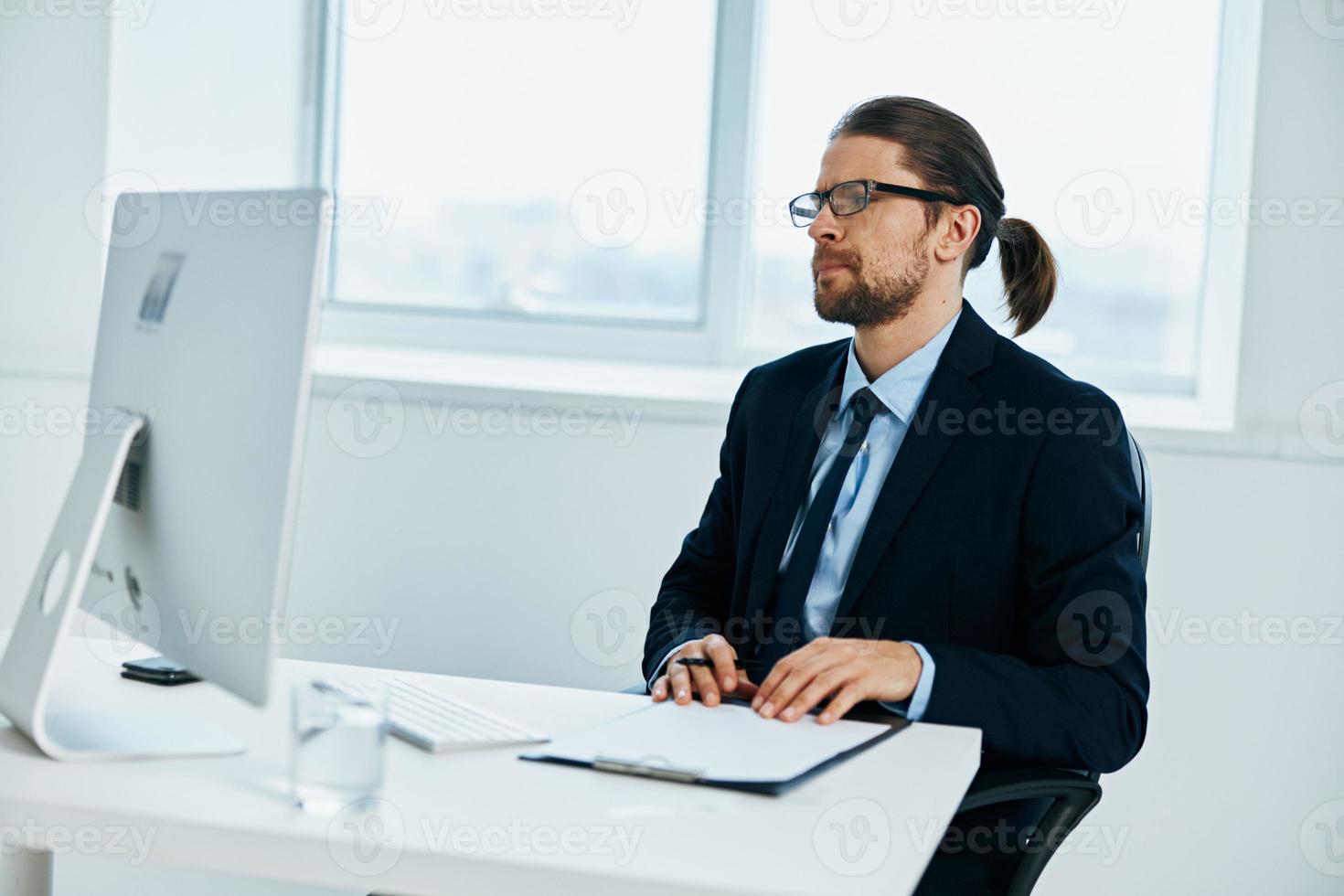 masculino gerente sentado a un escritorio en frente de un computadora ejecutivo foto