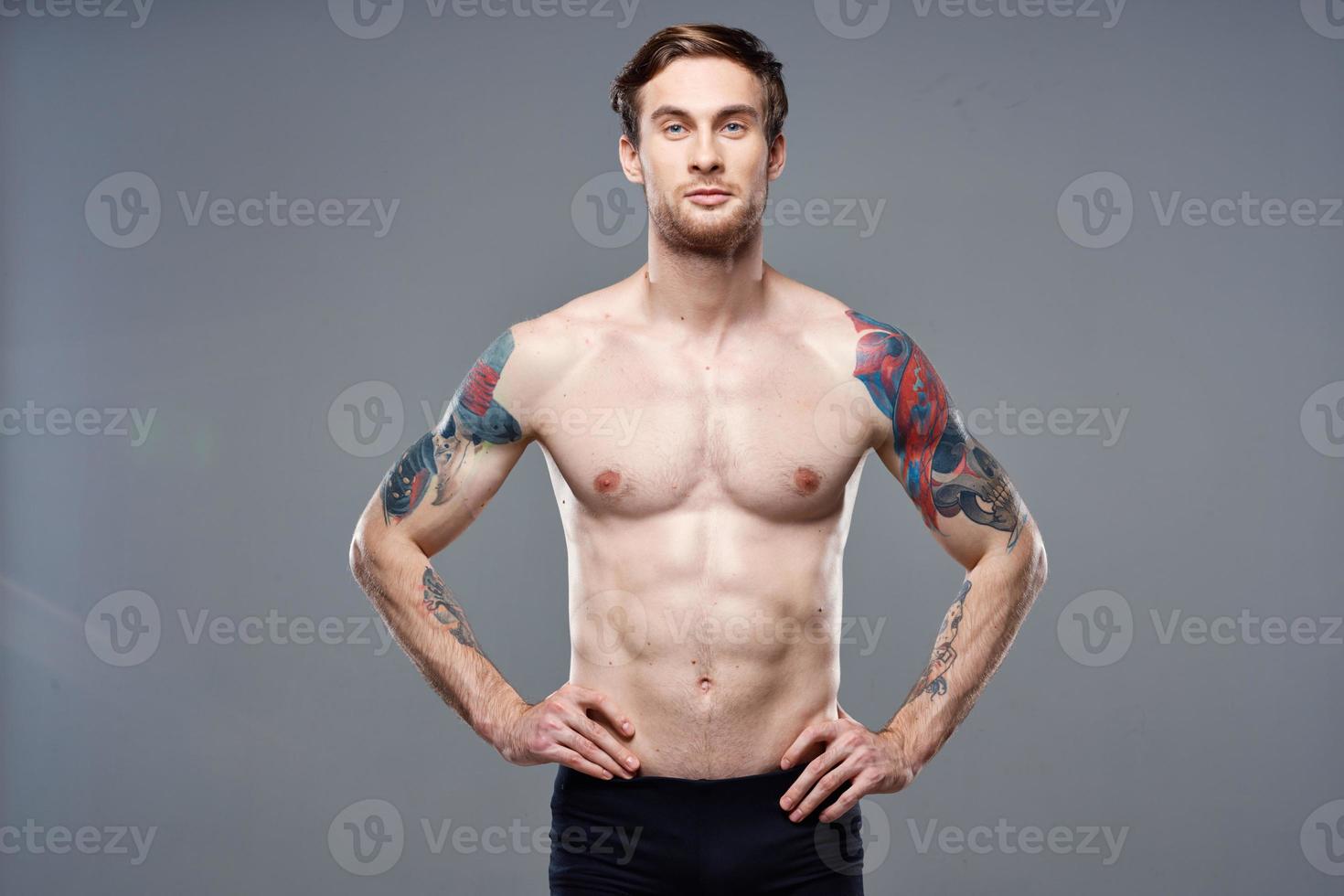 sporty man pumped up press acting out on his arms cropped view gray background photo