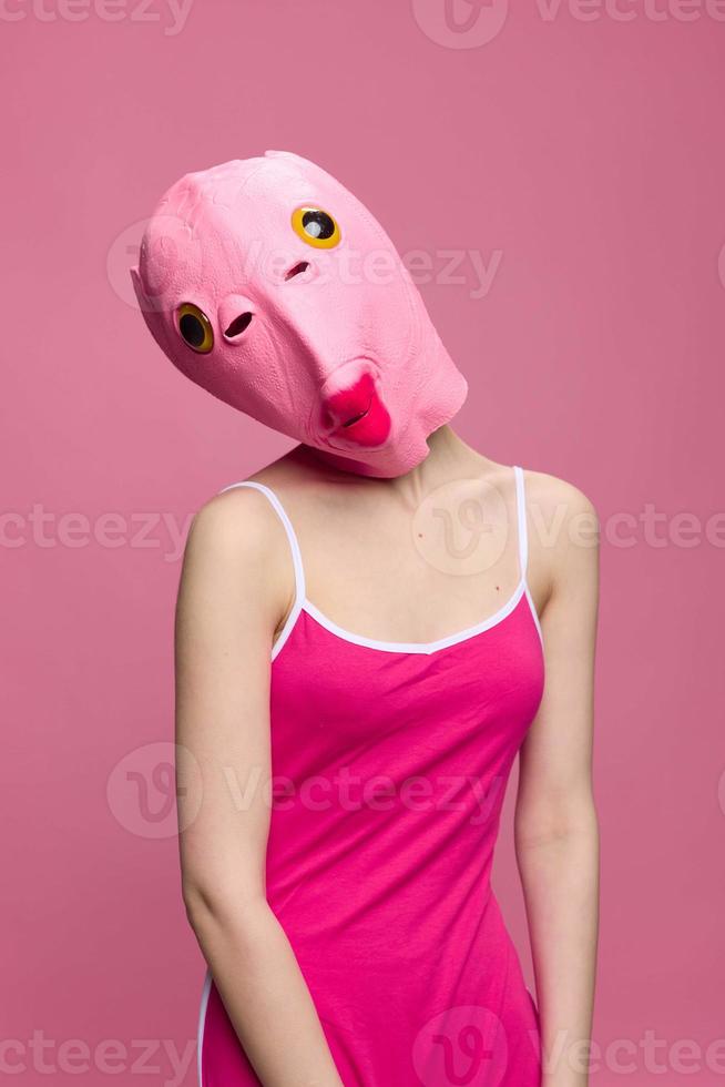 Conceptual art photo of a sexy woman in a fish mask for Halloween on a pink background