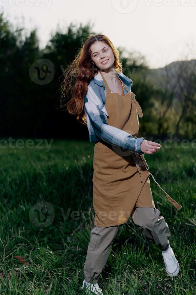 Woman farm worker in apron relaxing in nature and watching the sunset after a day of work on the farm photo