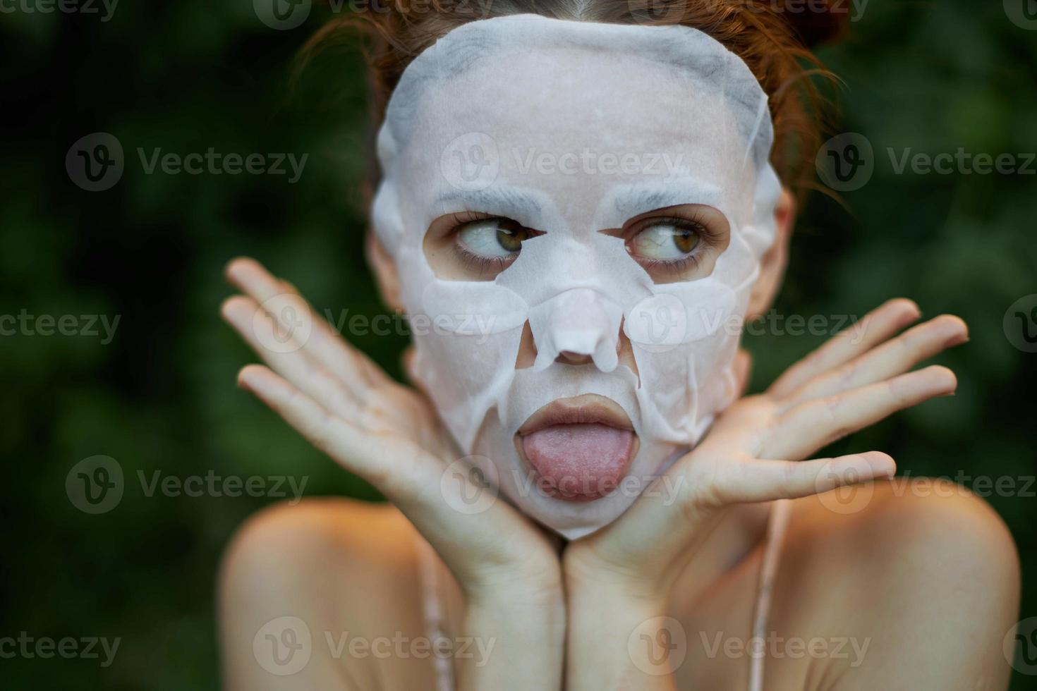 hermosa mujer anti-envejecimiento máscara palos fuera su lengua y mira lejos cosmetología foto