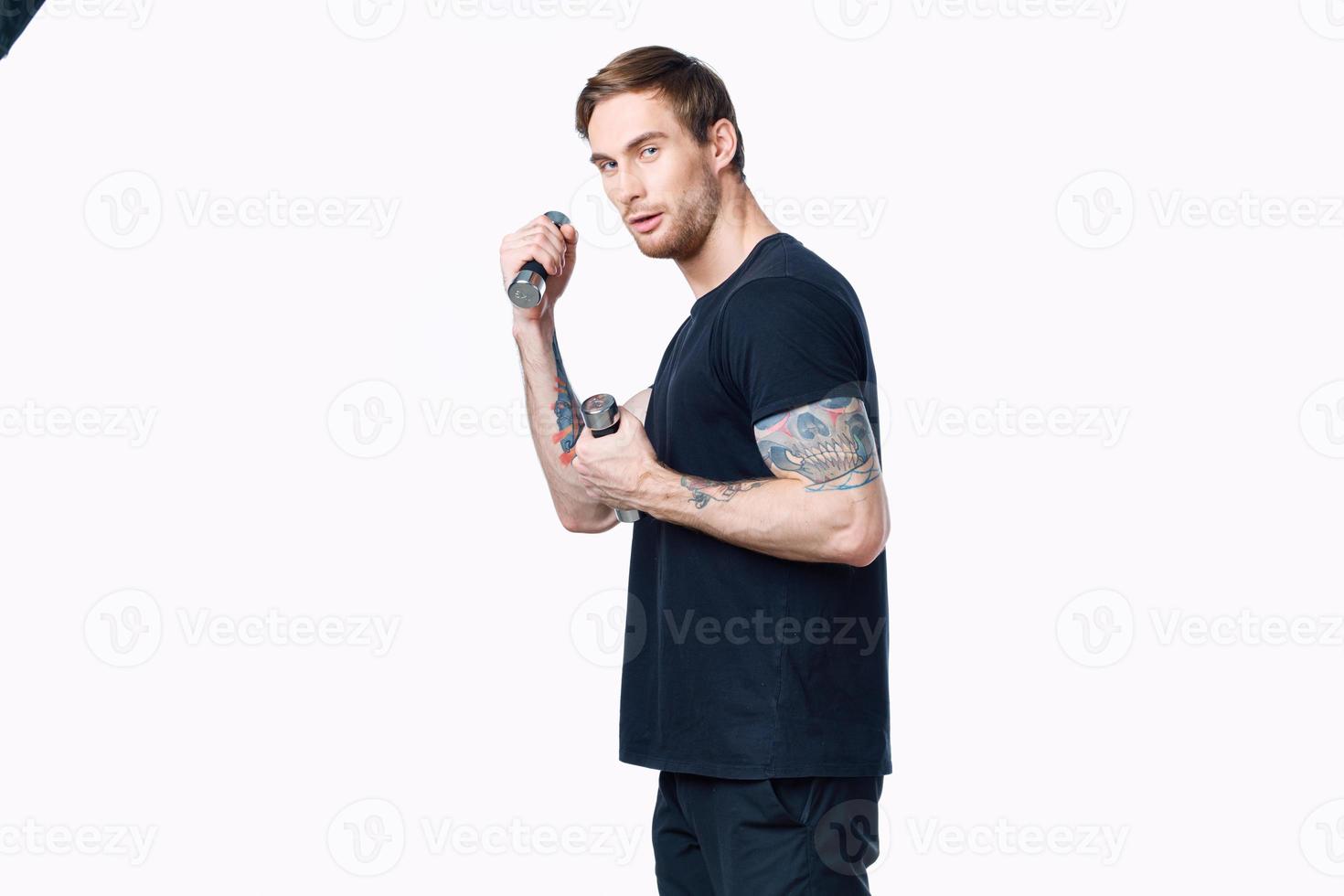 young man athlete in a black T-shirt with dumbbells in his hands side view Copy Space photo