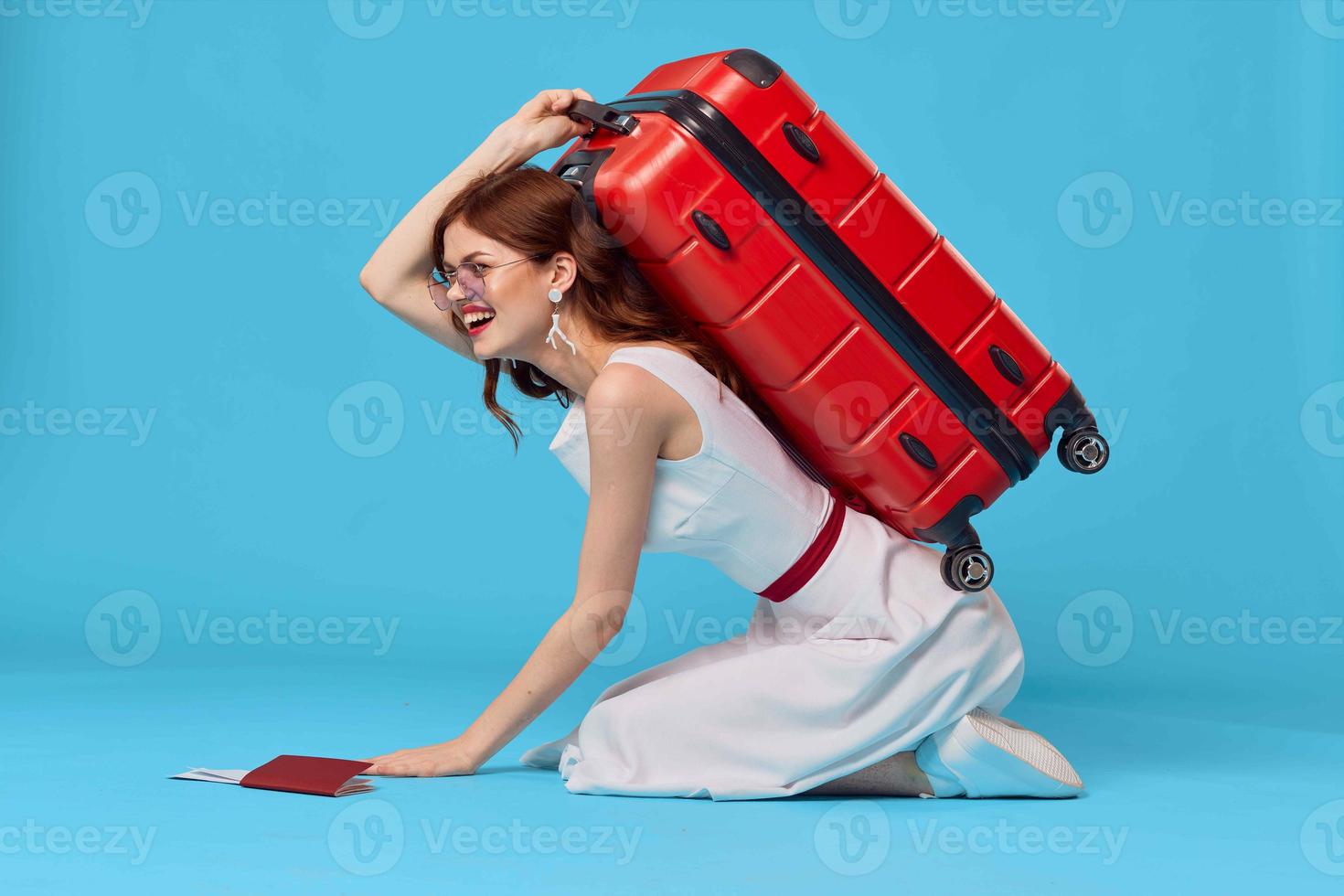 cheerful woman with red suitcase sitting on the floor emotions isolated background photo