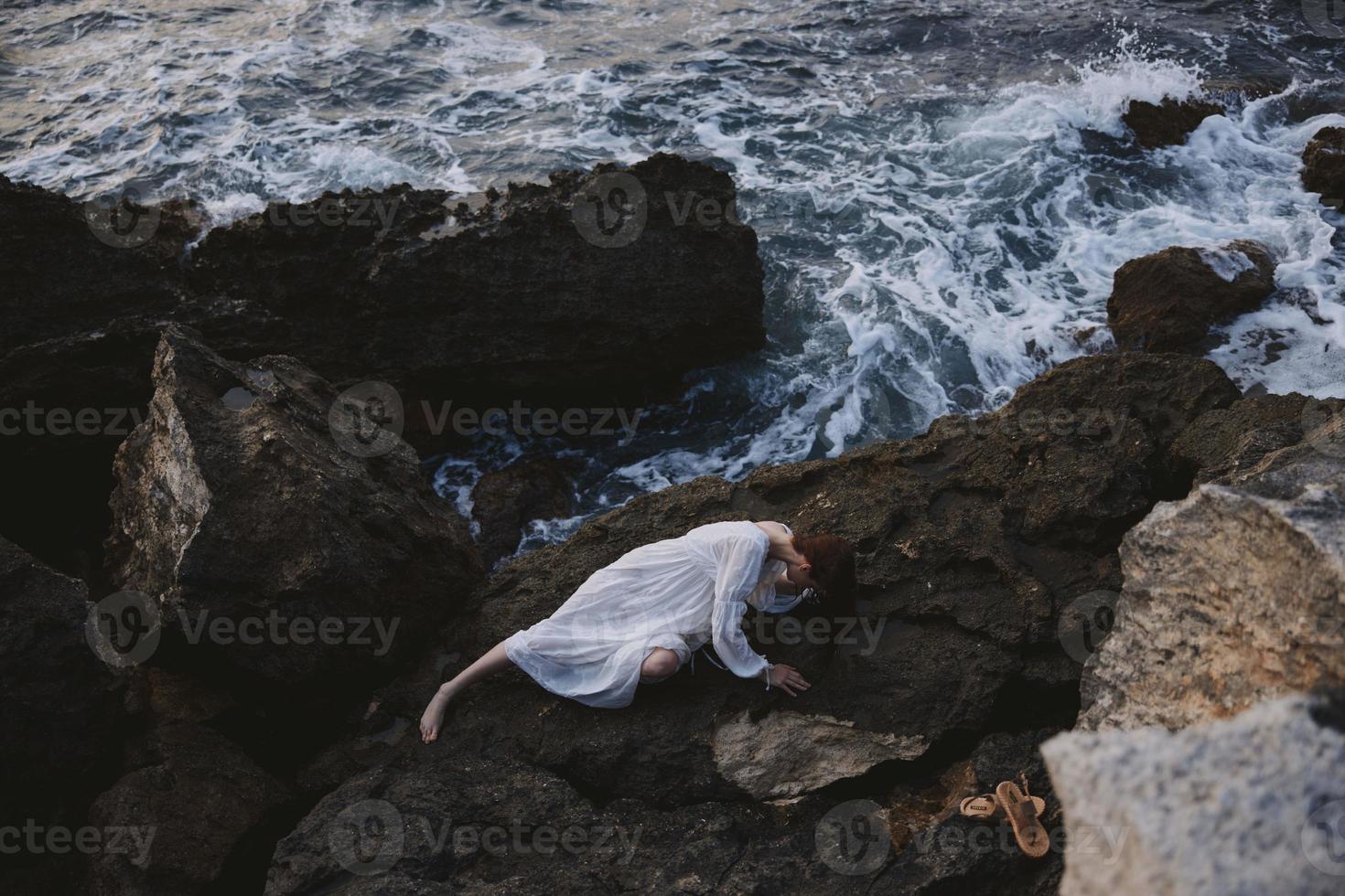 Beautiful bride in a secluded spot on a wild rocky coast in a white dress view from above photo