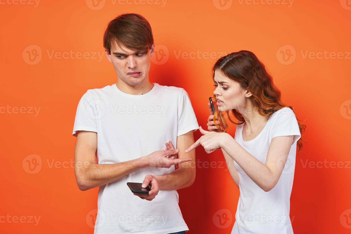 a man and a woman in white t-shirts holding telephones communication entertainment photo