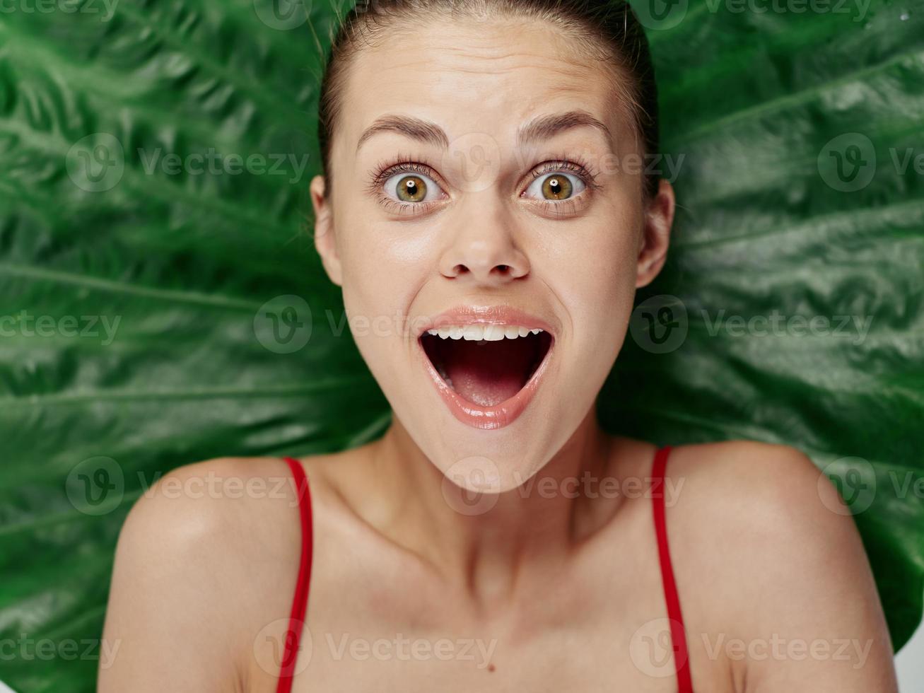 emotional woman with open mouth with bare shoulders palm leaf on background photo