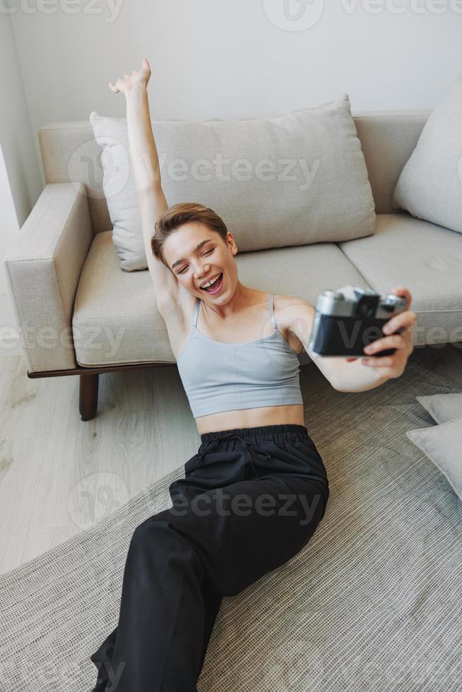 Happy smile woman holding an old camera and taking pictures of herself as a weekend photographer in home clothes with a short haircut hair without filters on a white background, free copy space photo