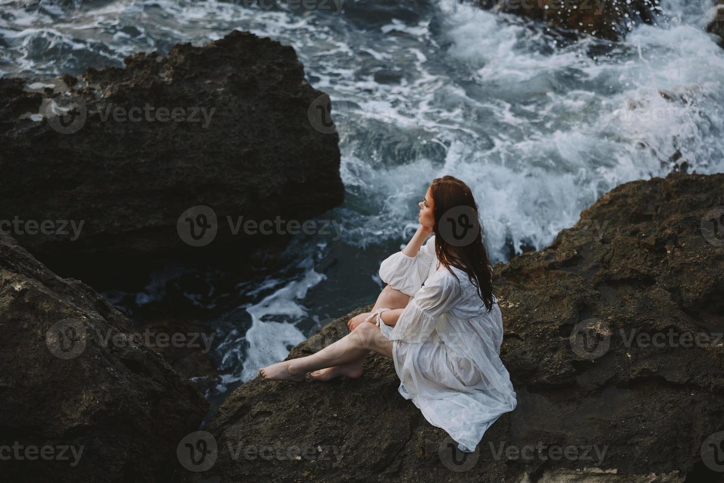 Woman in white wedding dress barefoot sitting on a stone nature photo