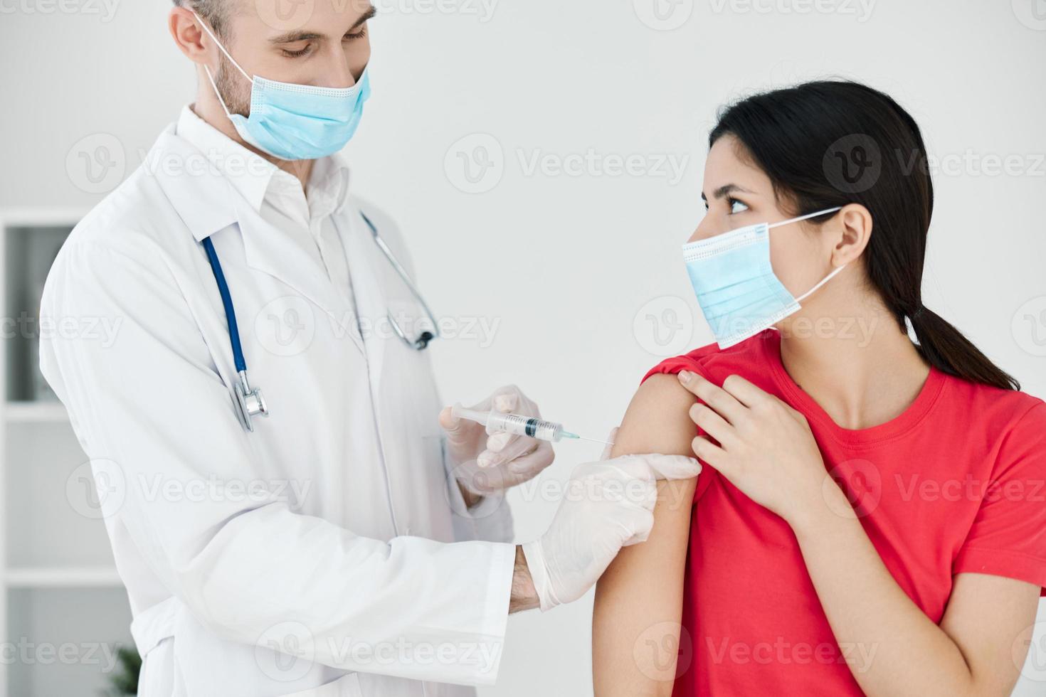 the doctor makes an injection into the patient's arm with a medical mask plan covid photo