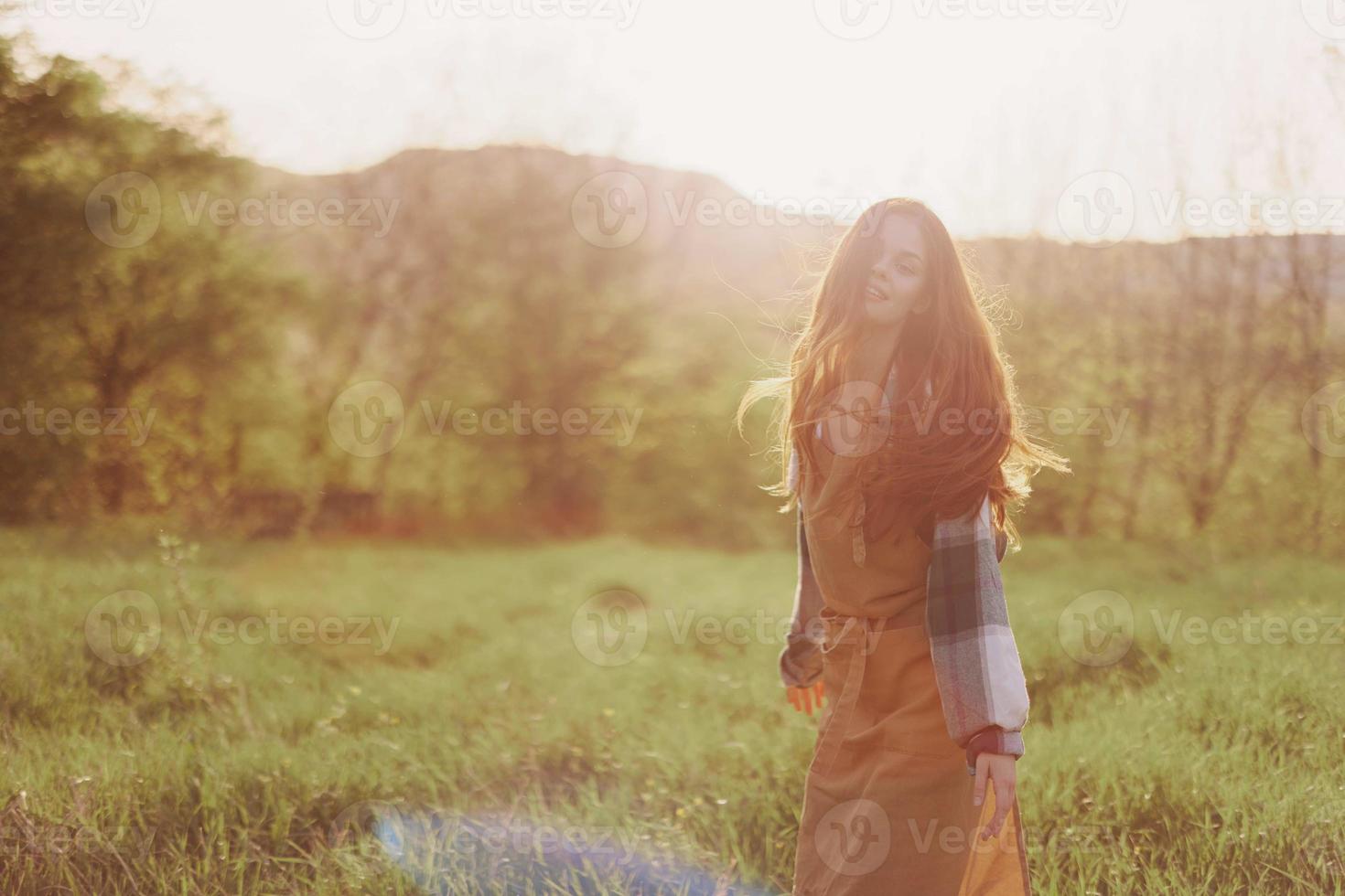A woman running through a field on a summer day with long flowing hair in the rays of the setting sun. The concept of freedom and harmony with nature photo