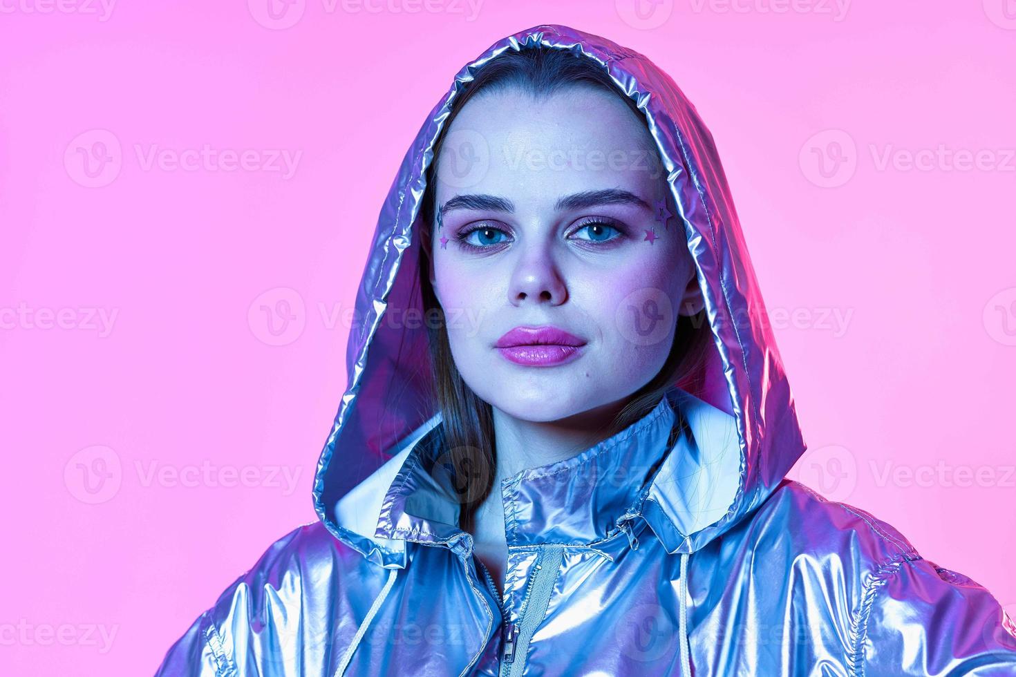 attractive woman silver hooded jacket makeup pink background neon photo