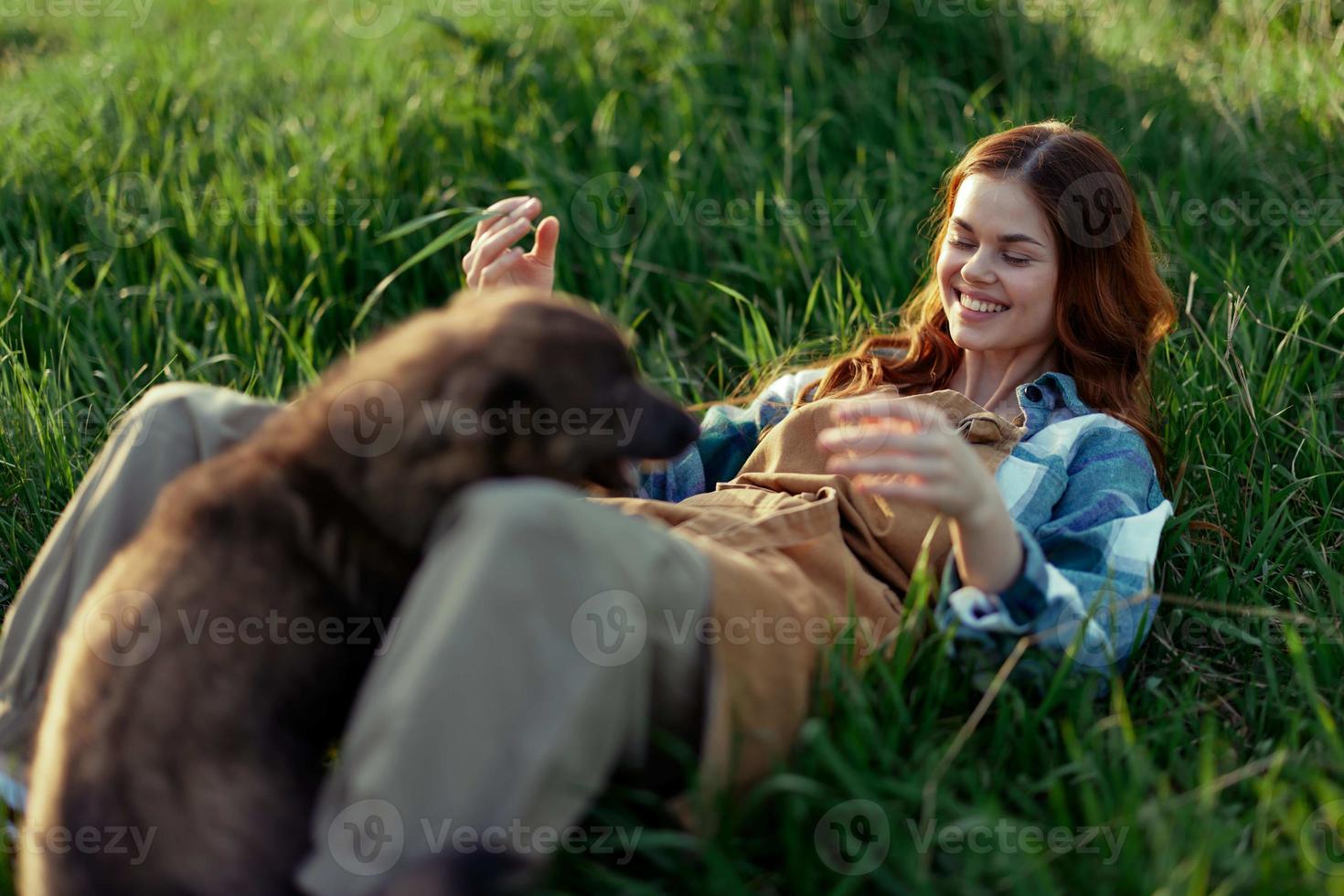 mujer juego con su perro en naturaleza sonriente y acostado en el verde césped en el parque, contento sano relación Entre amante y mascota foto