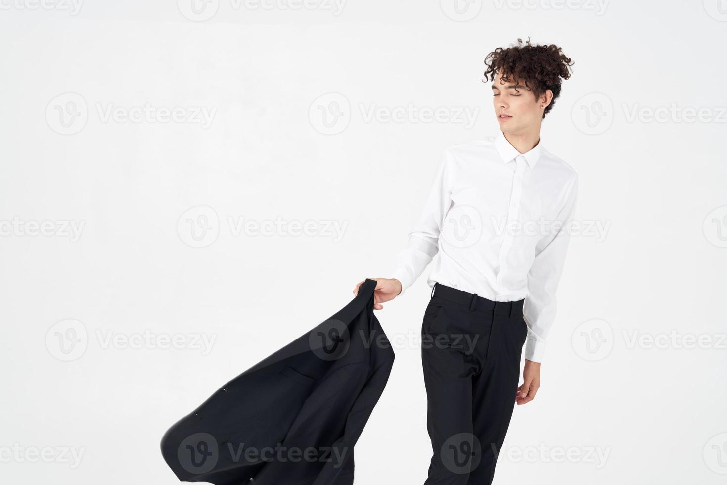 young man with curly hair and in a classic suit holds a jacket in his hand fashion style photography studio model photo