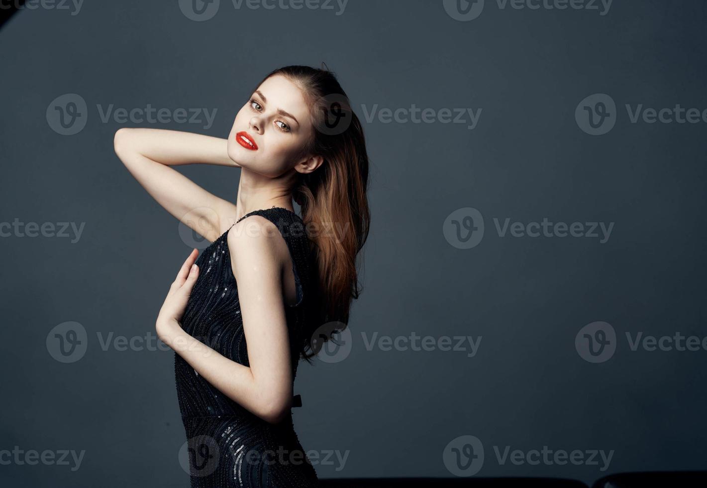 Red-haired Woman in a black dress posing on a gray background Copy Space Free Space photo