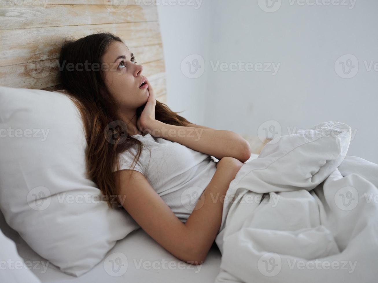 enfermo mujer mentiras en cama y mira a el techo emoción foto