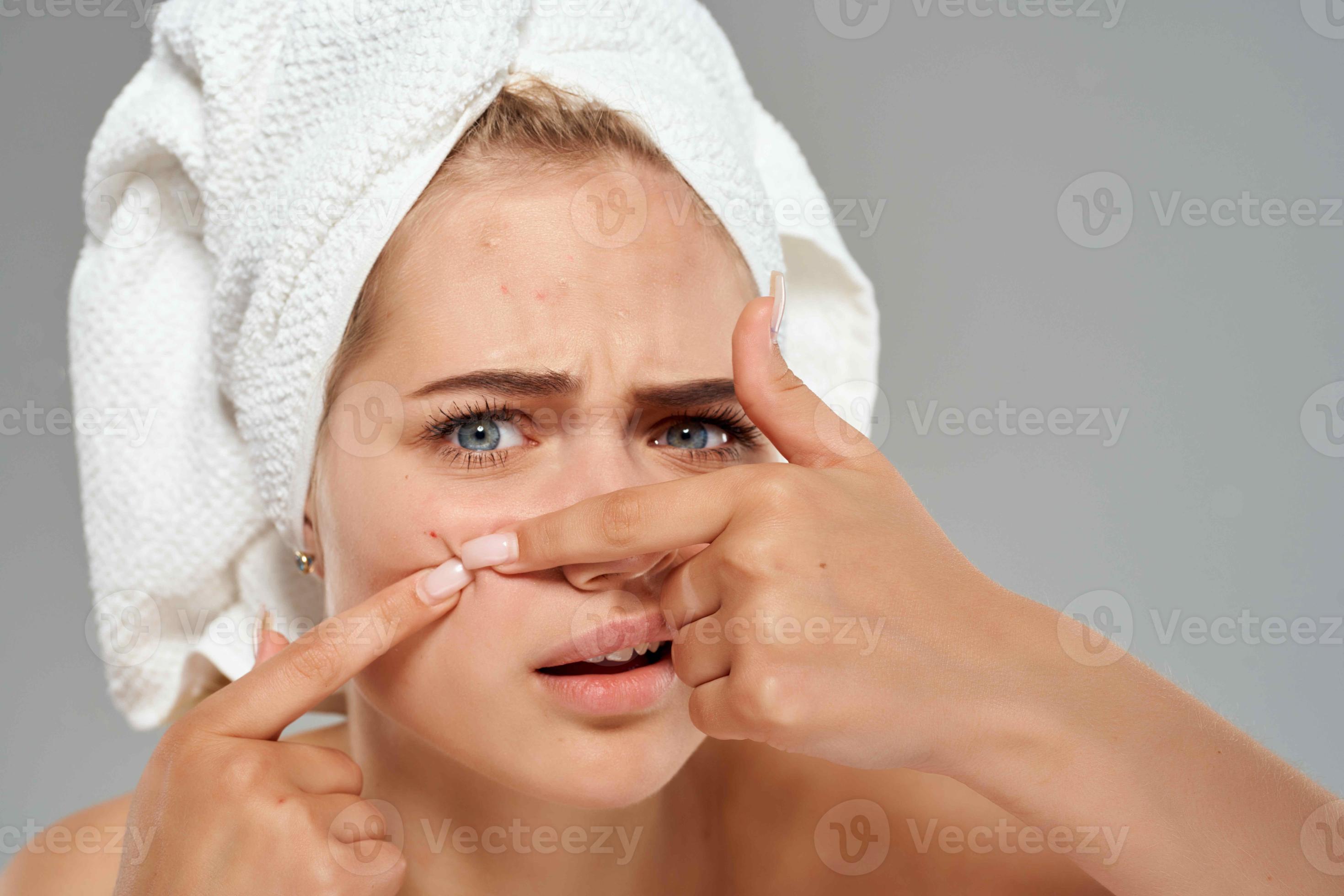 pretty woman with bare shoulders squeeze pimples on her face skin
