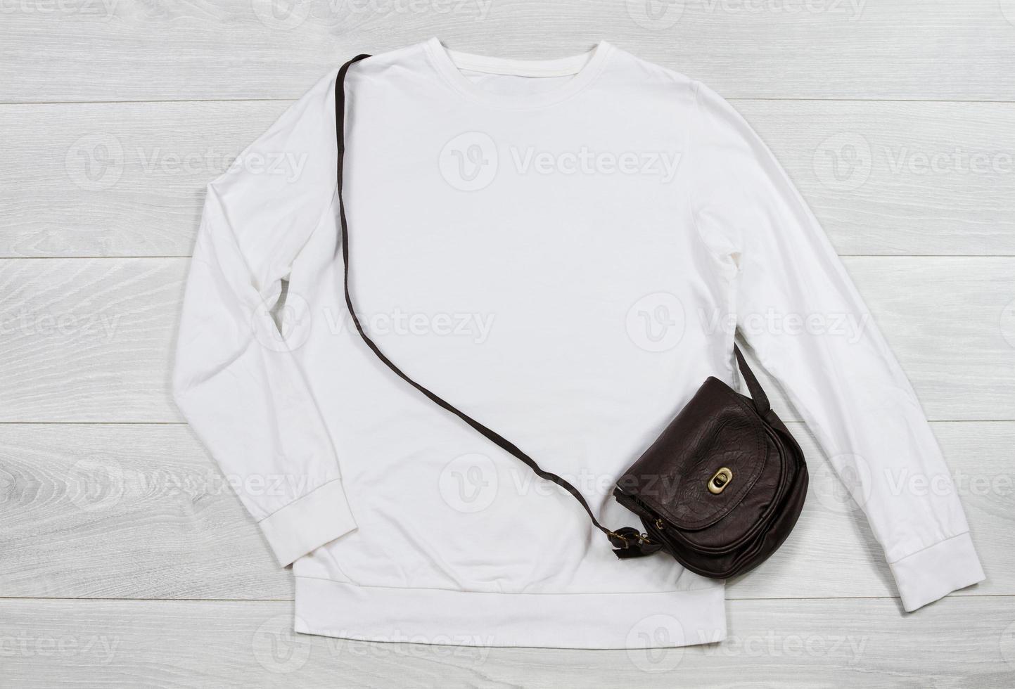 cerca arriba blanco blanco modelo camisa de entrenamiento capucha con Copiar espacio. parte superior ver Bosquejo pull-over en blanco de madera antecedentes. casual atuendo. plano laico modelo ropa. mujer accesorios foto